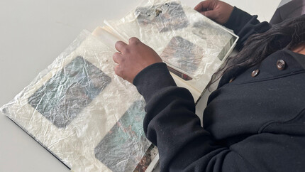 Iemand bekijkt een door brand beschadigd fotoalbum